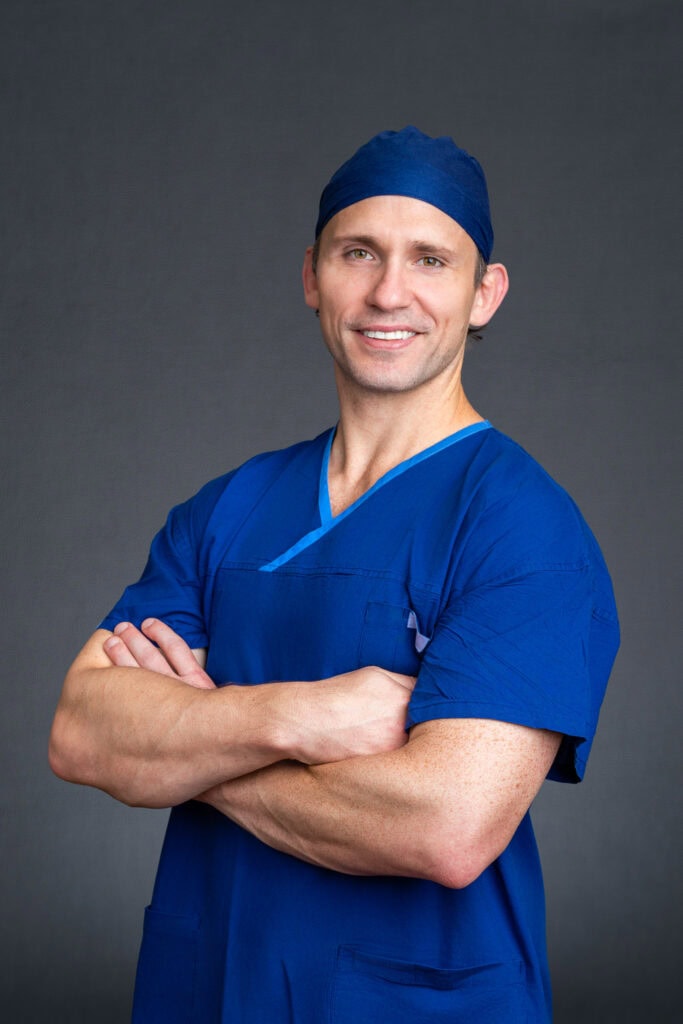 Sydney headshot of young orthopedic surgeon wearing his blue scrubs