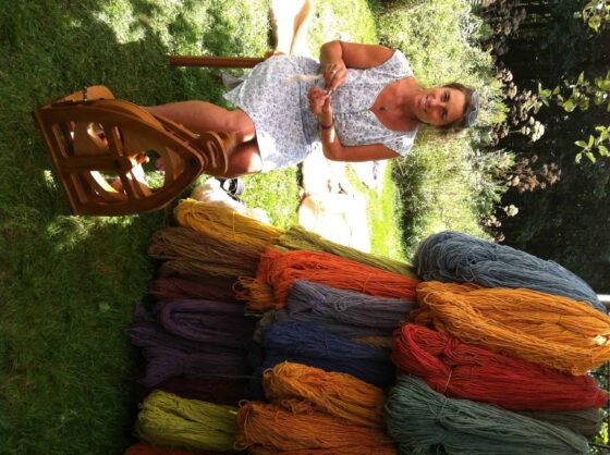 Colorful hand-dyed yarns displayed outdoors with a woman knitting, showcasing Seacolors Yarnery, perfect for vibrant, eco-friendly knitting projects and sustainable craft supplies.
