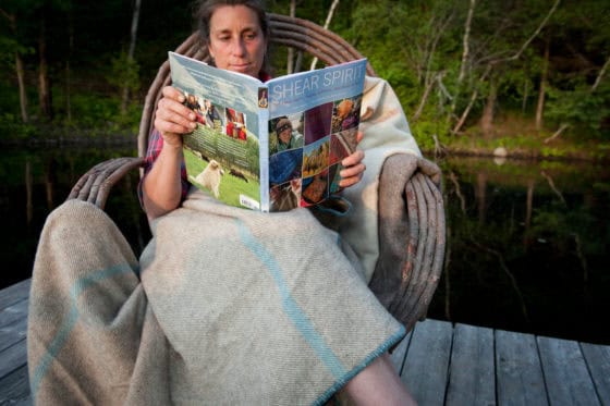 Handwoven Shearing Yarnery blanket displayed outdoors in natural setting on wooden dock, highlighting cozy artisanal textile craftsmanship and sustainable fiber art.