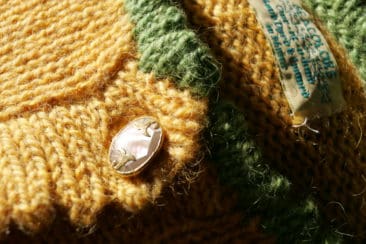 Soft yellow and green textured yarn from Seacolors Yarnery, featuring a mother of pearl button and a woven label, perfect for high-end knitting and crochet projects.
