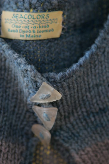 Seacolors Yarnery hand-dyed wool yarn from Maine with a textured knit fabric, showcasing artisanal craftsmanship and vibrant colors ideal for unique knitting projects.