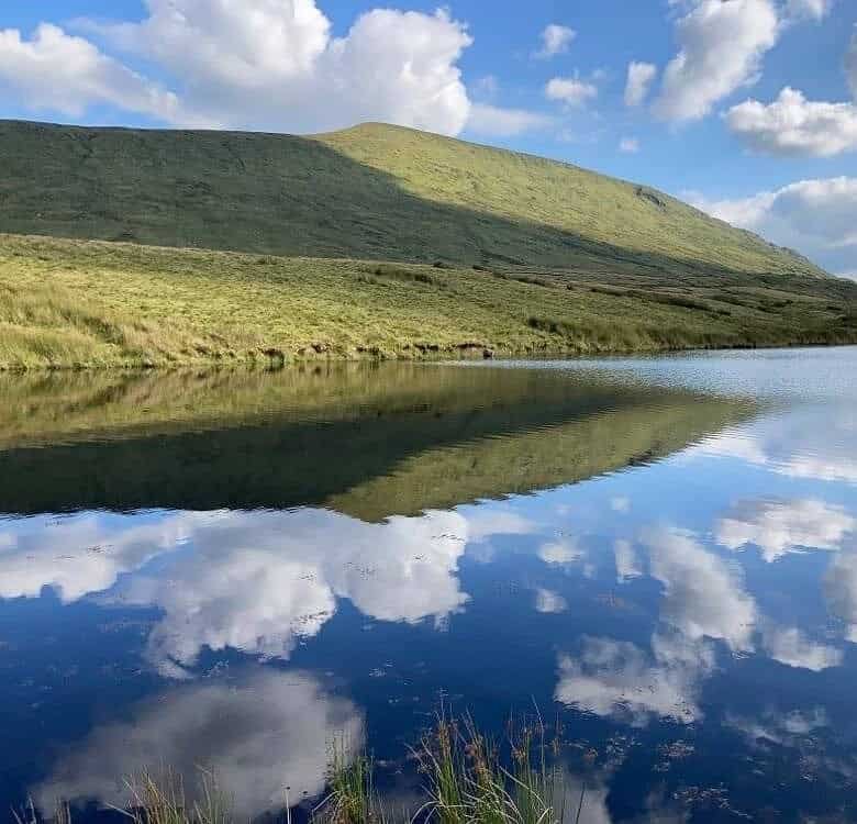 Scenic lake reflecting the sky with a green hill in County Mayo, Ireland. – Ghar.ie property listing