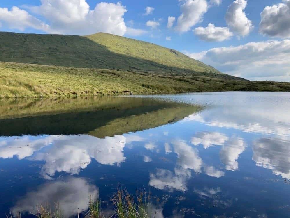 Scenic lake reflecting the sky with a green hill in County Mayo, Ireland. – Ghar.ie property listing