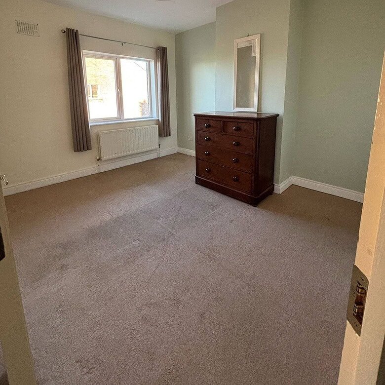 Bright bedroom in a Mullingar 3 bed property featuring a window and wooden dresser. – Ghar.ie property listing