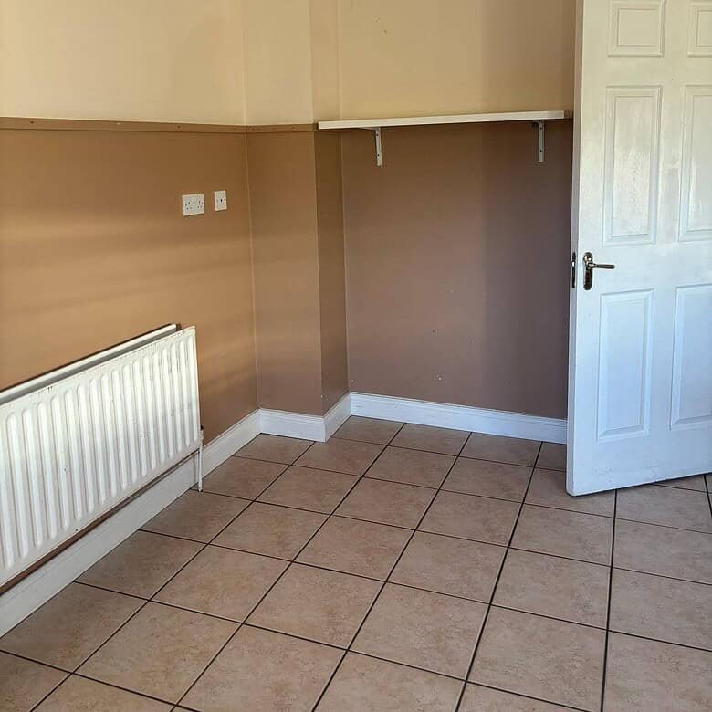 Mullingar bright bedroom with neutral walls, tiled floor, radiator, and white door and shelf. – Ghar.ie property listing