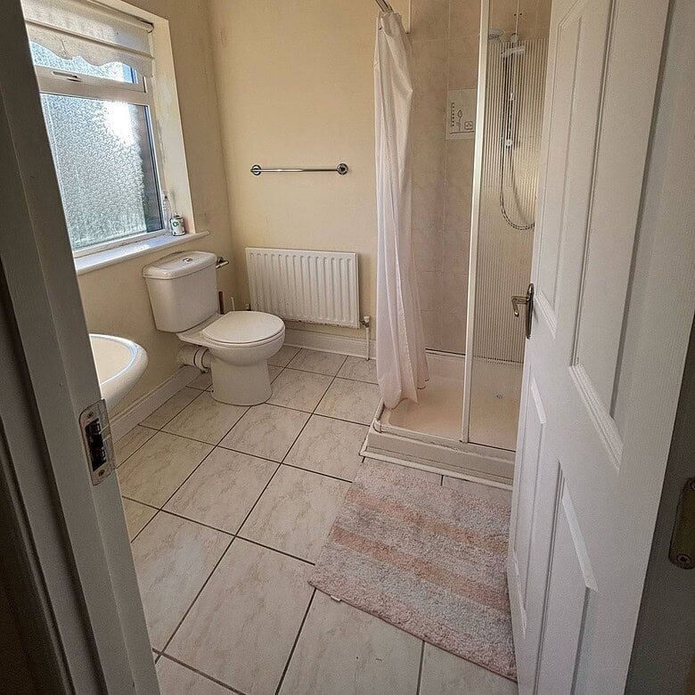 Bathroom in the Mullingar property with a shower, toilet, sink, and window providing natural light. – Ghar.ie property listing