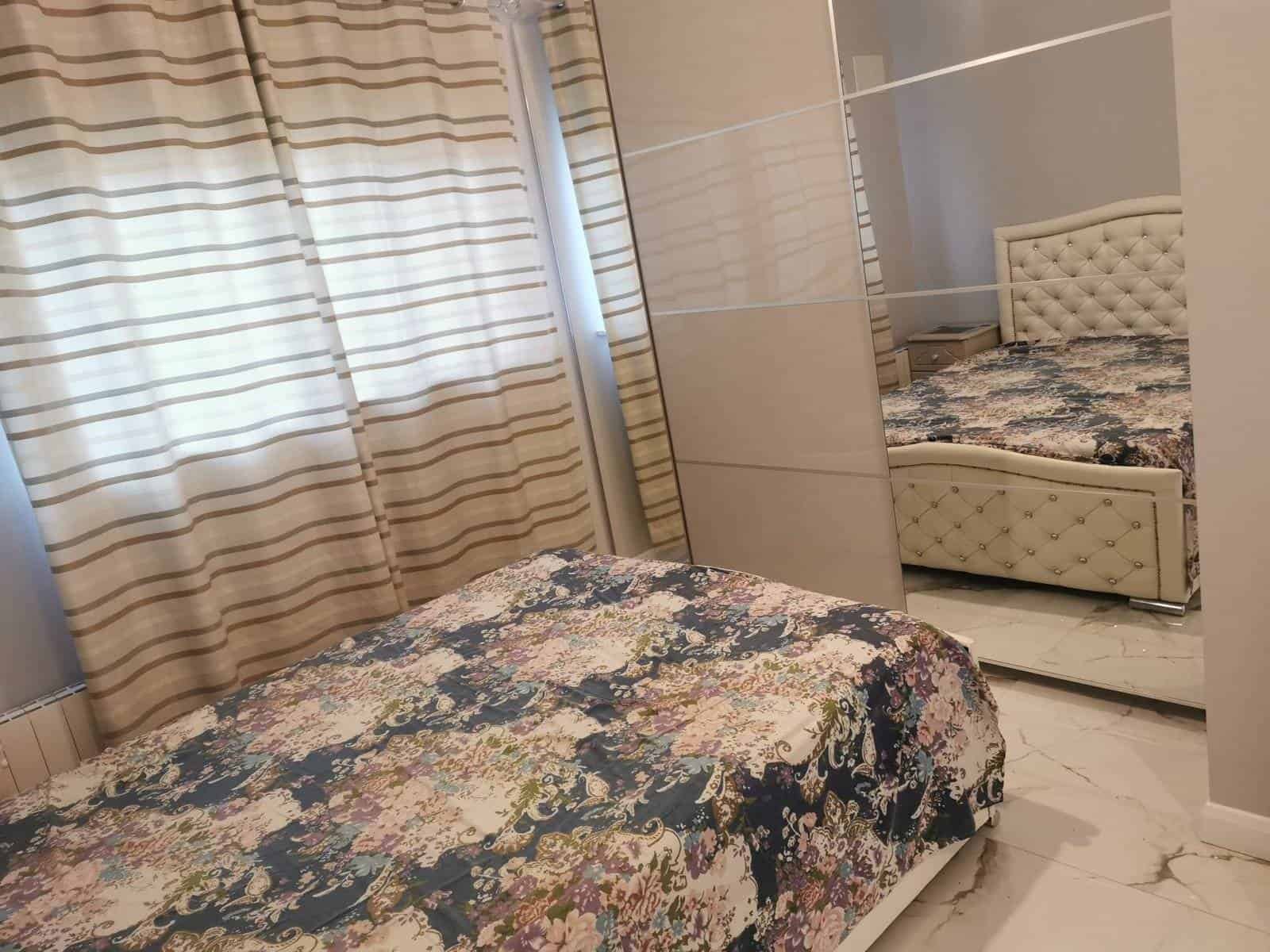 Bedroom in a one-bedroom apartment with a bed, curtains, and a mirrored wardrobe. – Ghar.ie property listing