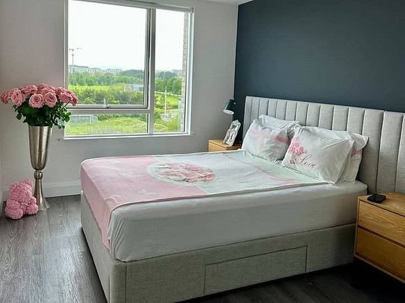 Bedroom with a double bed, pink floral accents, and a large window in a Dublin room for rent. – Ghar.ie property listing