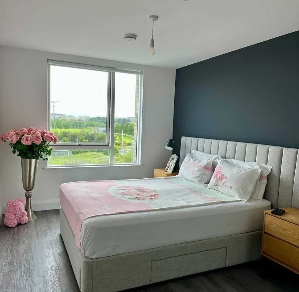 Bedroom with a double bed, pink floral accents, and a large window in a Dublin room for rent. – Ghar.ie property listing