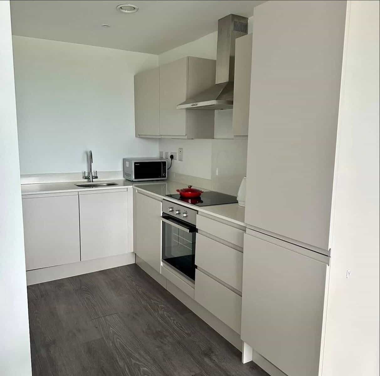 Modern kitchen with white cabinets, stainless steel appliances, and dark wood flooring in Dublin. – Ghar.ie property listing