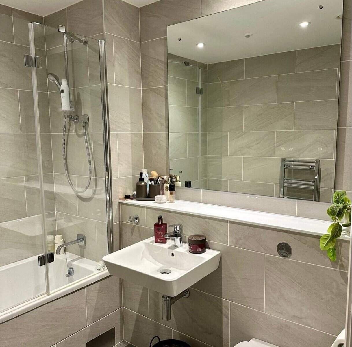 Modern bathroom with grey tiles, a square sink, and a glass-enclosed bathtub and shower. – Ghar.ie property listing