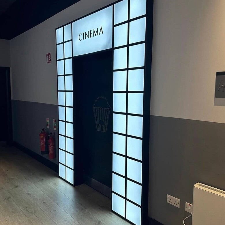 Cinema entrance with illuminated frame and popcorn graphic on the door, creating an inviting atmosphere. – Ghar.ie property listing