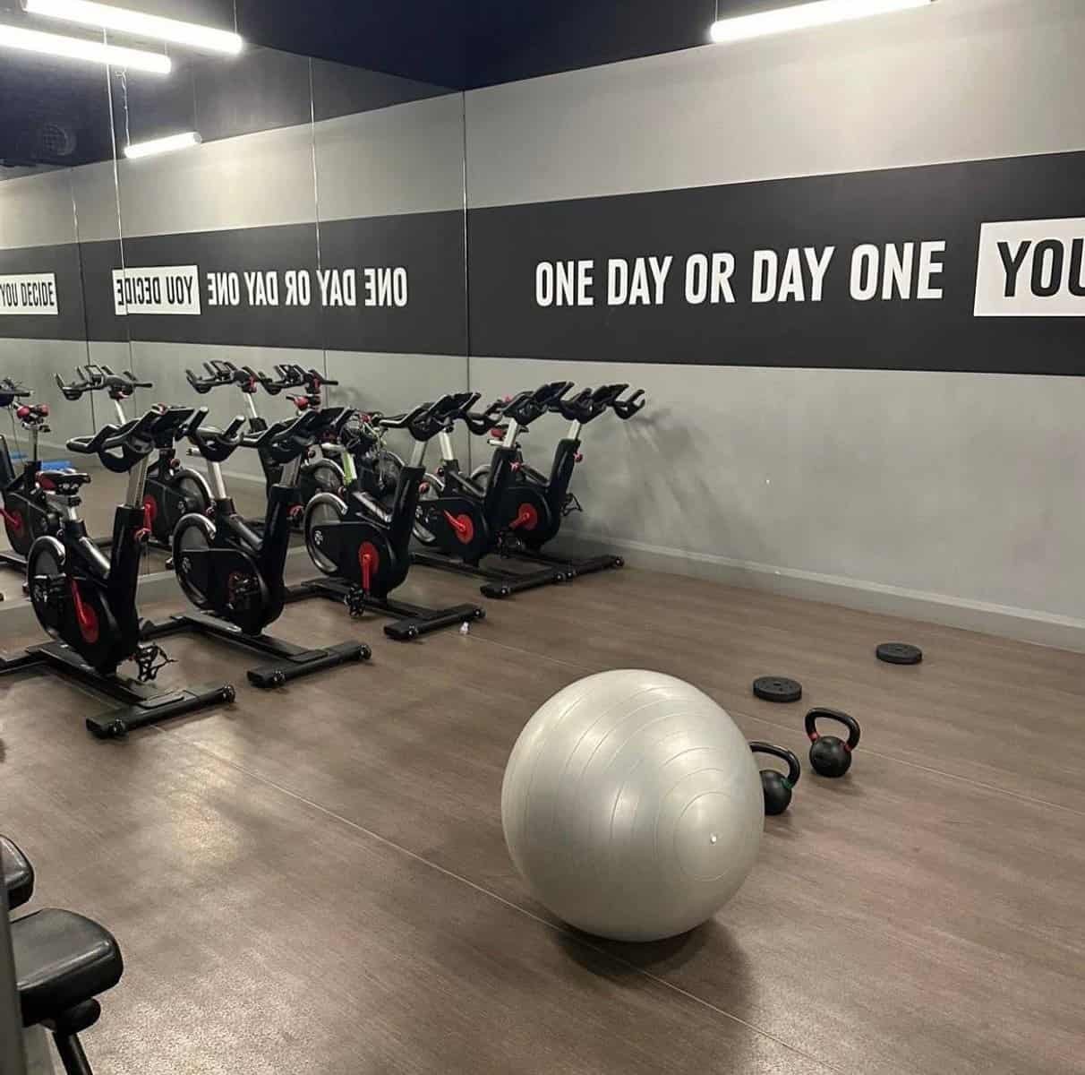 Gym with exercise bikes, weights, and a large silver exercise ball. Motivational text on wall. – Ghar.ie property listing