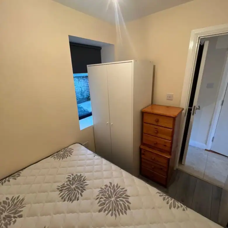 Bedroom in a Phibsborough flat for rent, featuring a bed, wardrobe, and chest of drawers. – Ghar.ie property listing