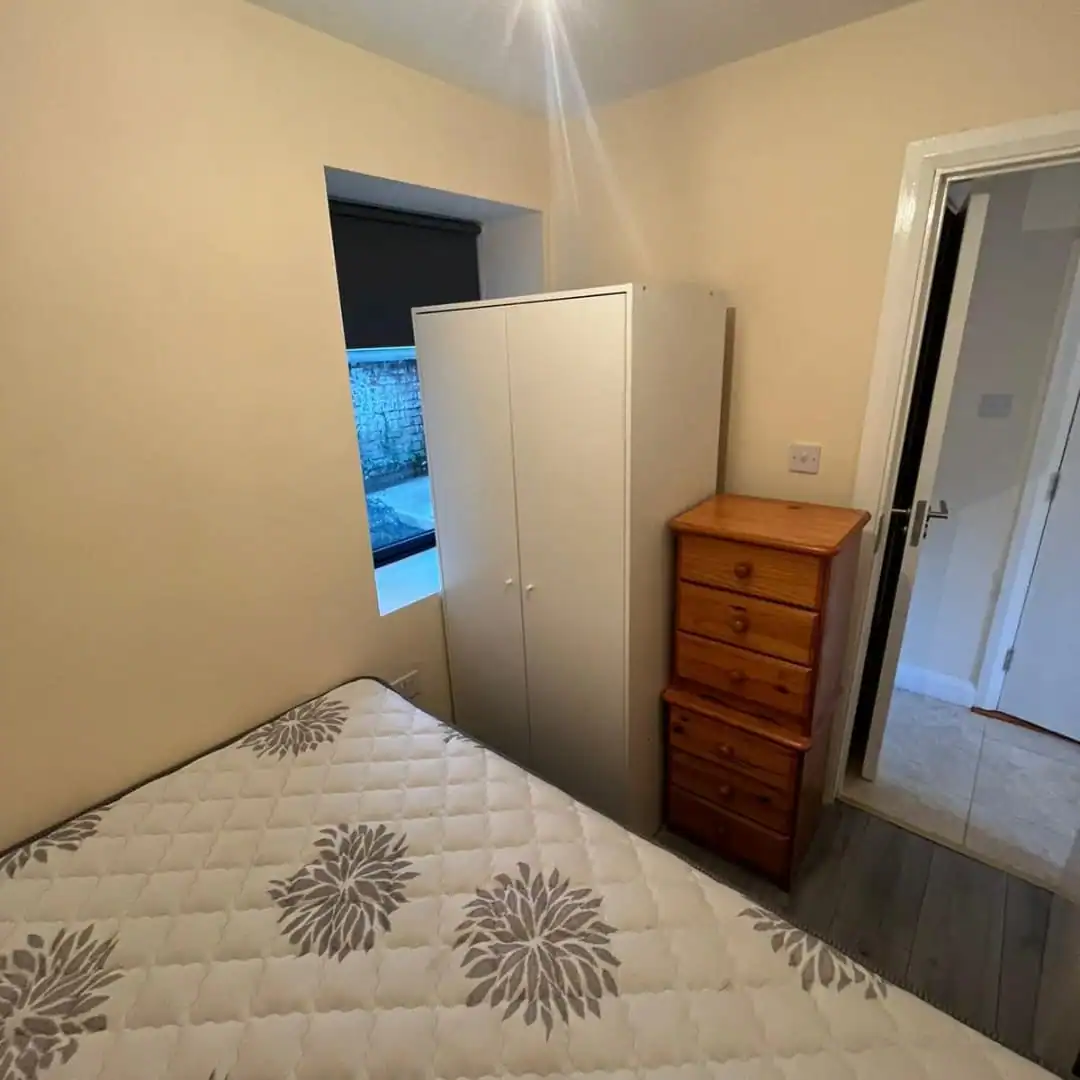 Bedroom in a Phibsborough flat for rent, featuring a bed, wardrobe, and chest of drawers. – Ghar.ie property listing