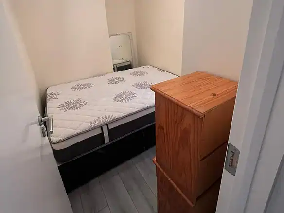 Phibsborough flat for rent: A small bedroom with a bed, wardrobe, and chest of drawers. – Ghar.ie property listing