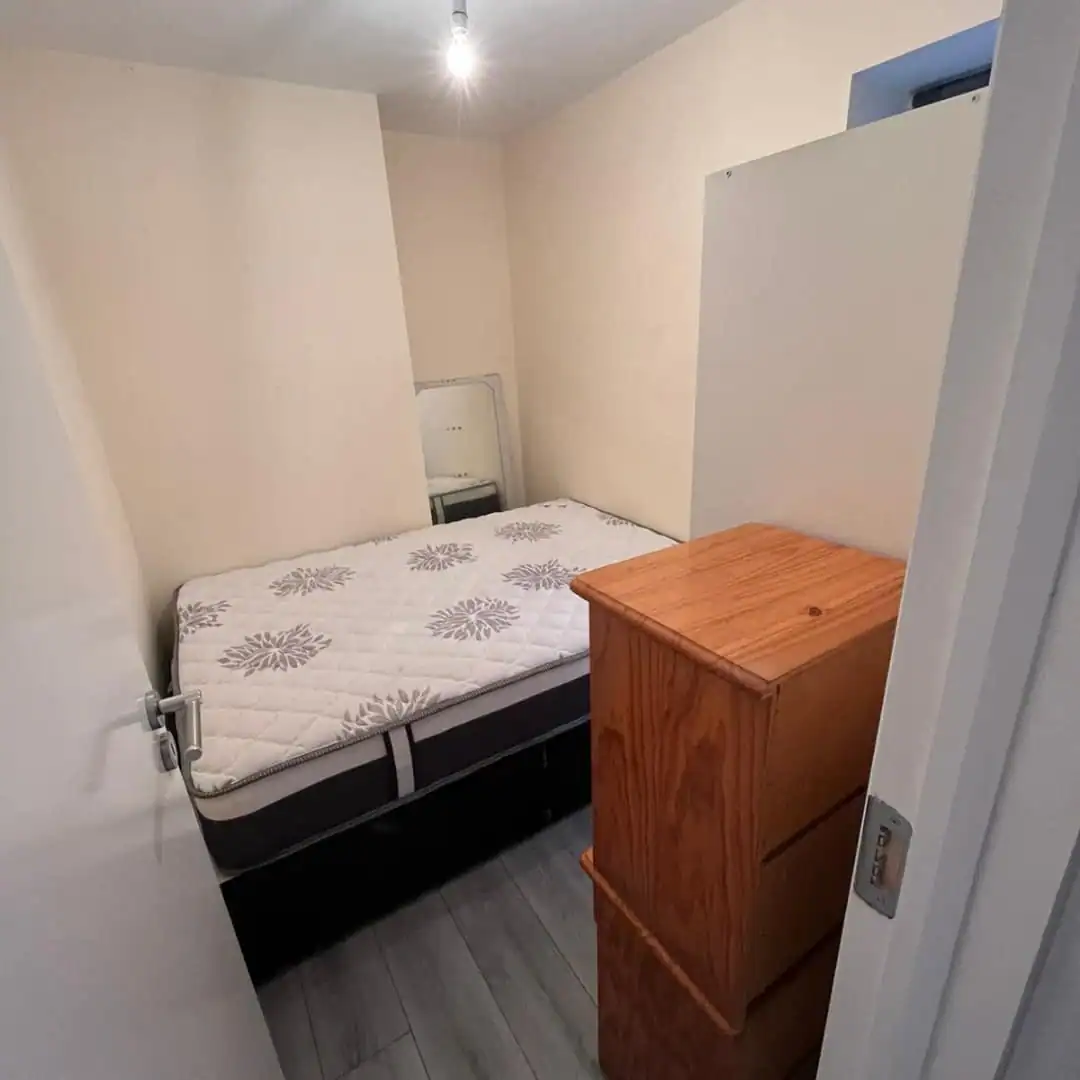 Phibsborough flat for rent: A small bedroom with a bed, wardrobe, and chest of drawers. – Ghar.ie property listing