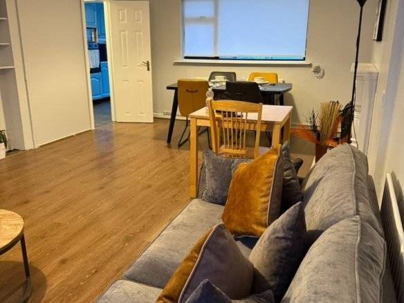 Living room with grey sofa, wooden floor, desk, and chairs in a Dublin 11 property. – Ghar.ie property listing