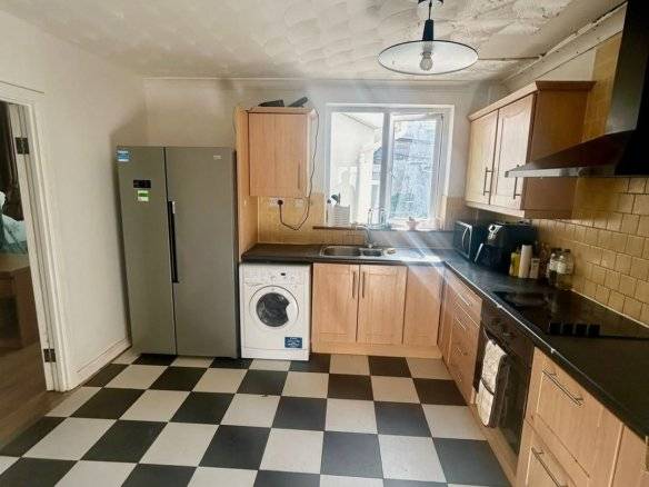 Kitchen with checkerboard floor, fridge, washing machine, and wooden cabinets in Tallaght, Dublin 24. – Ghar.ie property listing