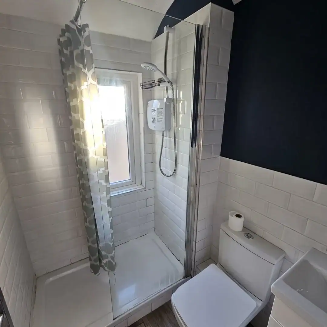 Bathroom with shower, toilet, sink, white tile, and shower curtain in a Drimnagh apartment. – Ghar.ie property listing