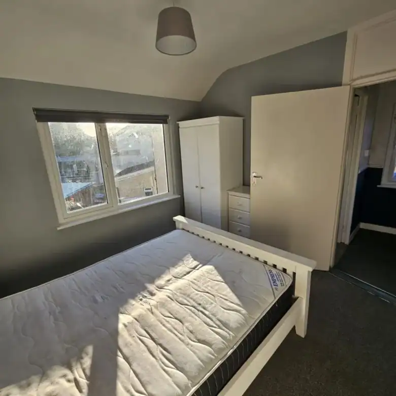 Bedroom in a Drimnagh apartment for rent, featuring a bed, wardrobe, and window with natural light. – Ghar.ie property listing