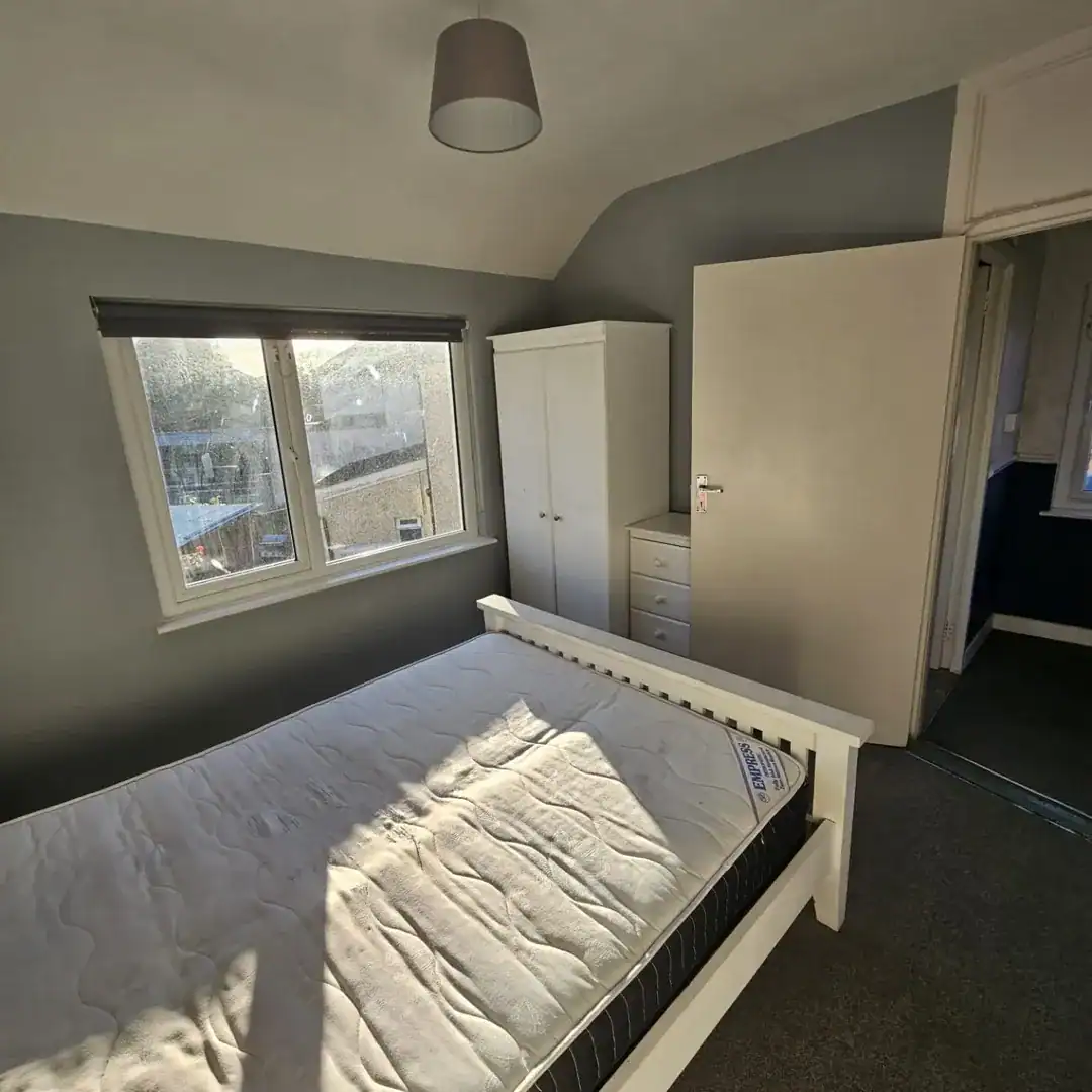 Bedroom in a Drimnagh apartment for rent, featuring a bed, wardrobe, and window with natural light. – Ghar.ie property listing