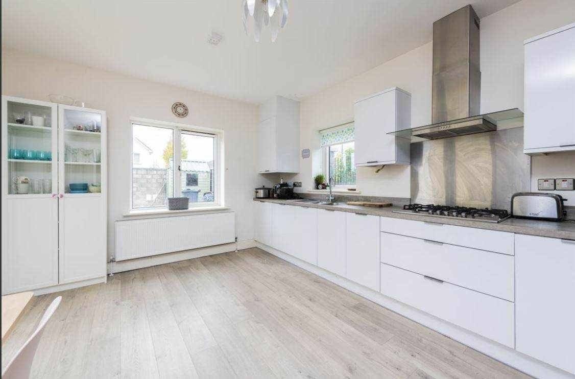 Bright kitchen with white cabinets, light wood floors, and a window, showcasing modern design. – Ghar.ie property listing