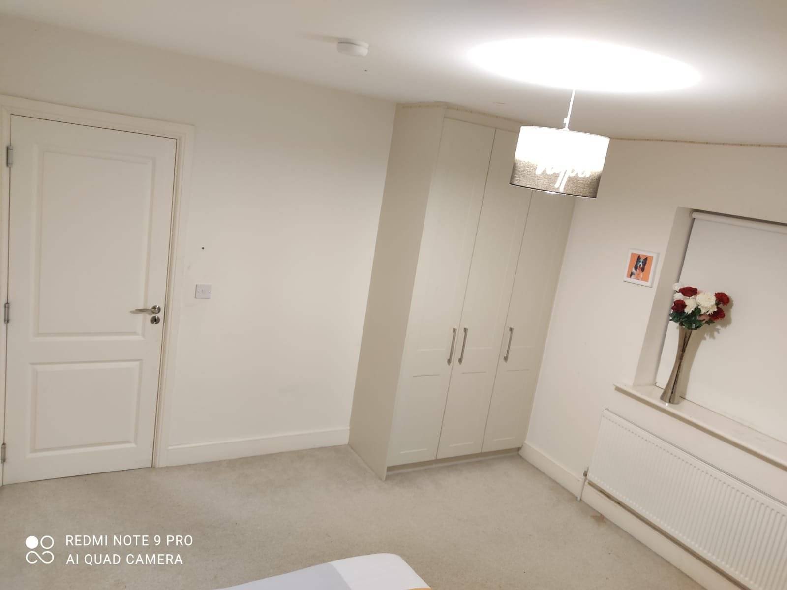 Private single occupancy bedroom with a wardrobe, door, radiator, flowers, and overhead lighting. – Ghar.ie property listing
