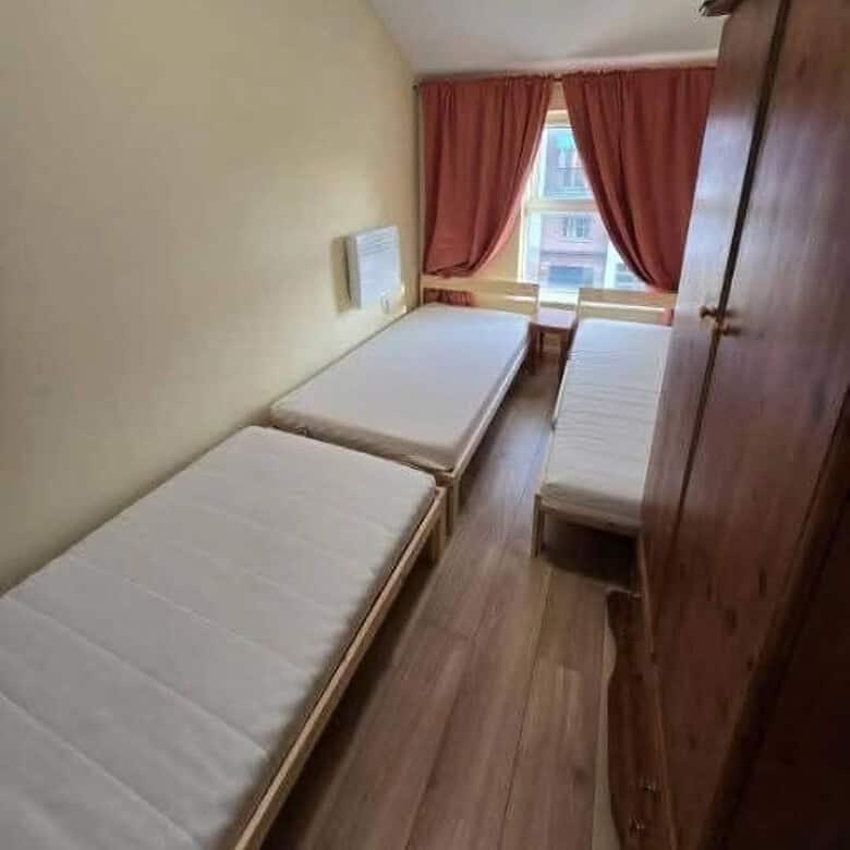Bedroom in Dublin 1 rental featuring three single beds, wooden floors, and a wardrobe. – Ghar.ie property listing