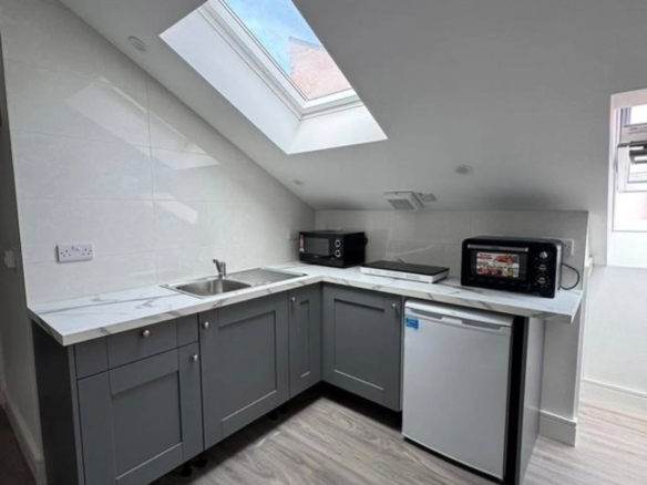 Compact studio kitchen with grey cabinets, white countertops, and a skylight in Dublin 7. – Ghar.ie property listing