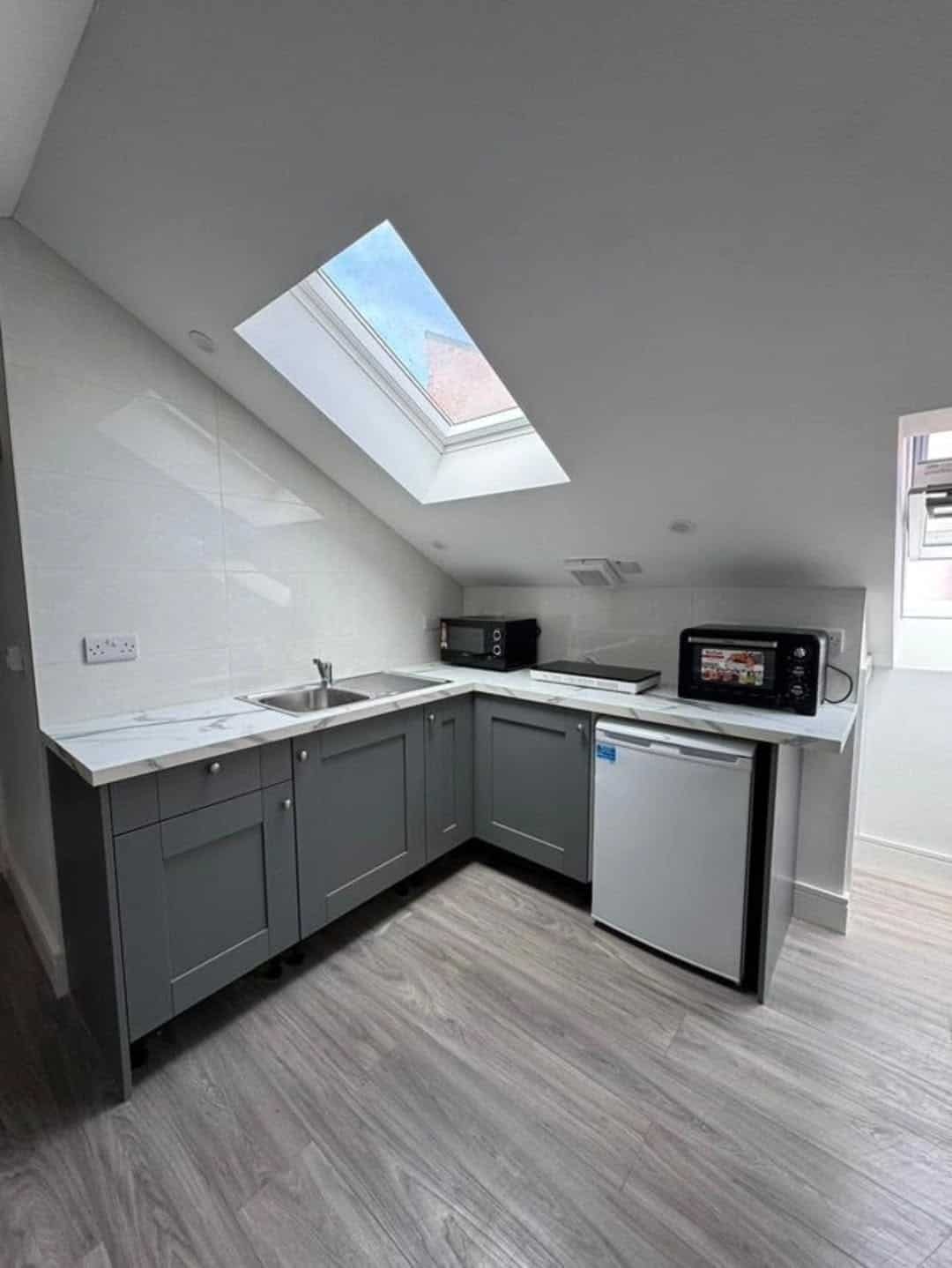 Compact studio kitchen with grey cabinets, white countertops, and a skylight in Dublin 7. – Ghar.ie property listing