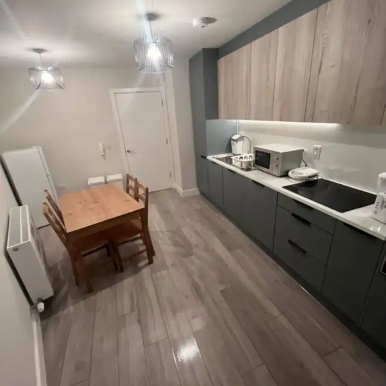 Kitchen and dining area in Blanchardstown, D15, featuring a wooden table, modern cabinets, and appliances. – Ghar.ie property listing