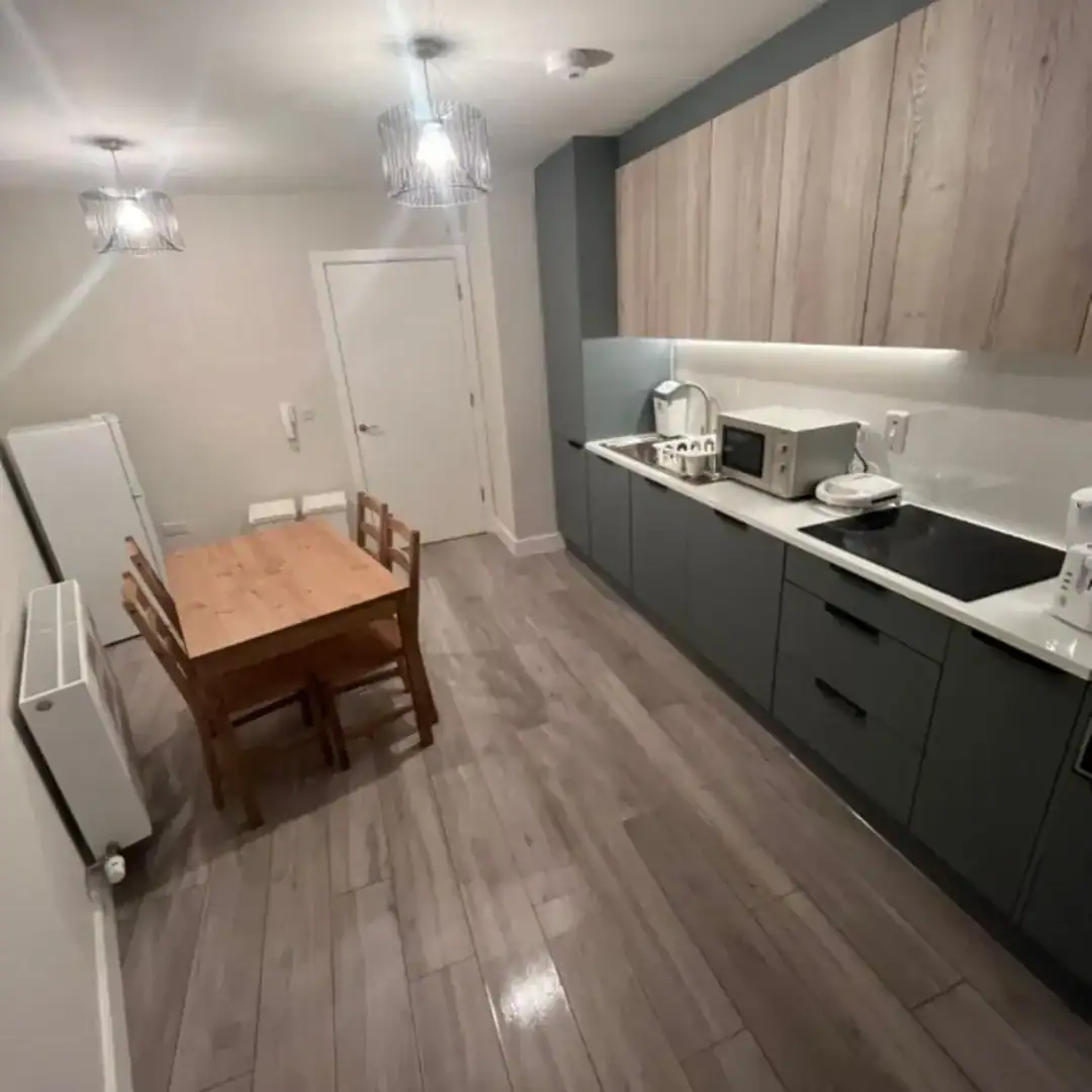 Kitchen and dining area in Blanchardstown, D15, featuring a wooden table, modern cabinets, and appliances. – Ghar.ie property listing