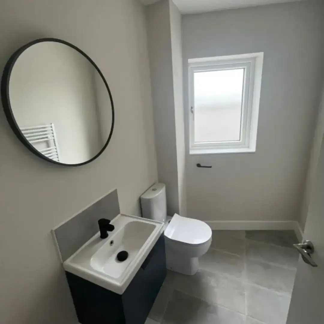 Modern bathroom with a round mirror, toilet, and sink in a Blanchardstown property. – Ghar.ie property listing