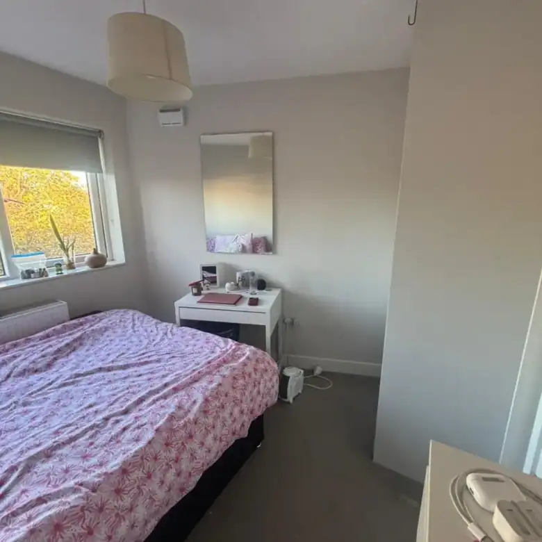 Bright bedroom with a double bed, desk, mirror, and window in Blanchardstown, D15. – Ghar.ie property listing