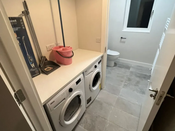 Laundry room with washing machine, cleaning supplies, and toilet in the Blanchardstown property. – Ghar.ie property listing