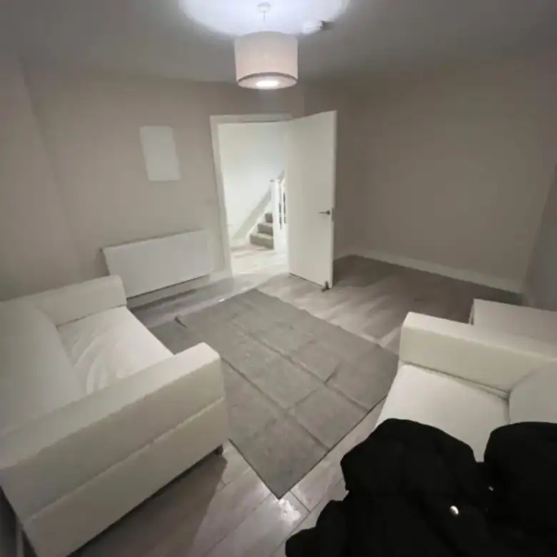 Living room in Blanchardstown with two white sofas, a grey rug, and a doorway to the stairs. – Ghar.ie property listing