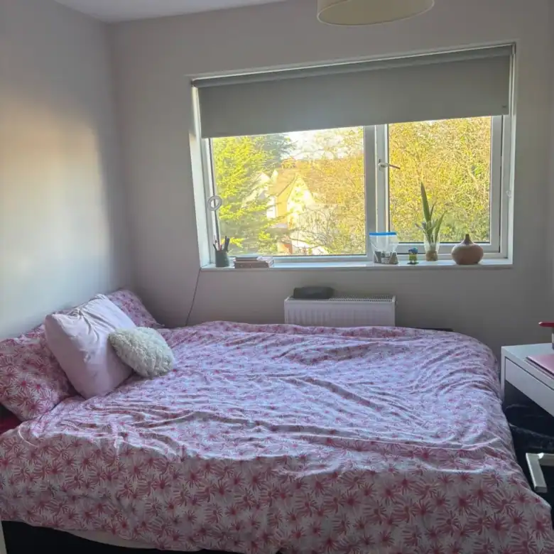 Cozy bedroom in Blanchardstown with a double bed, pink patterned duvet, and window view. – Ghar.ie property listing