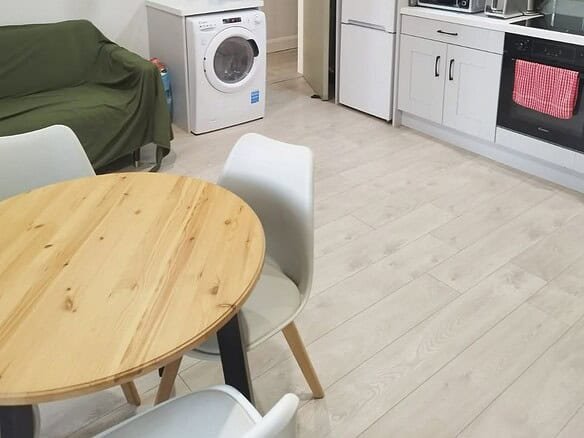 Shared kitchen with dining table, washing machine, and white cabinets, showcasing the single bed vacancy. – Ghar.ie property listing