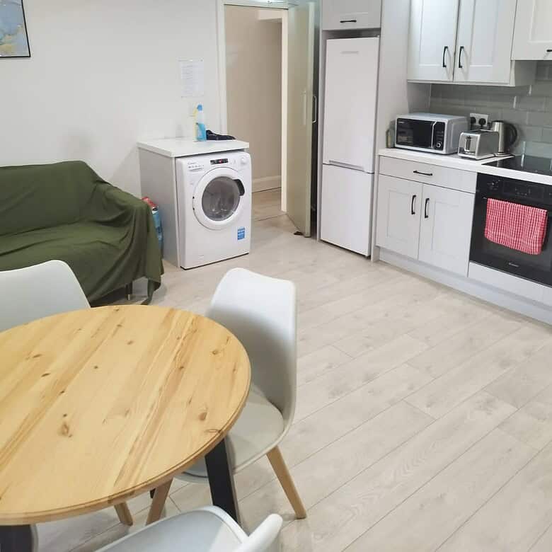 Shared kitchen with dining table, washing machine, and white cabinets, showcasing the single bed vacancy. – Ghar.ie property listing
