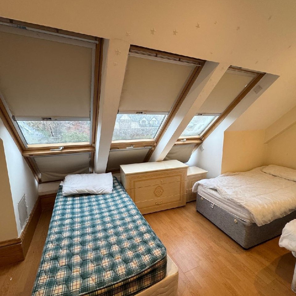 Attic bedroom with two beds and skylight windows.