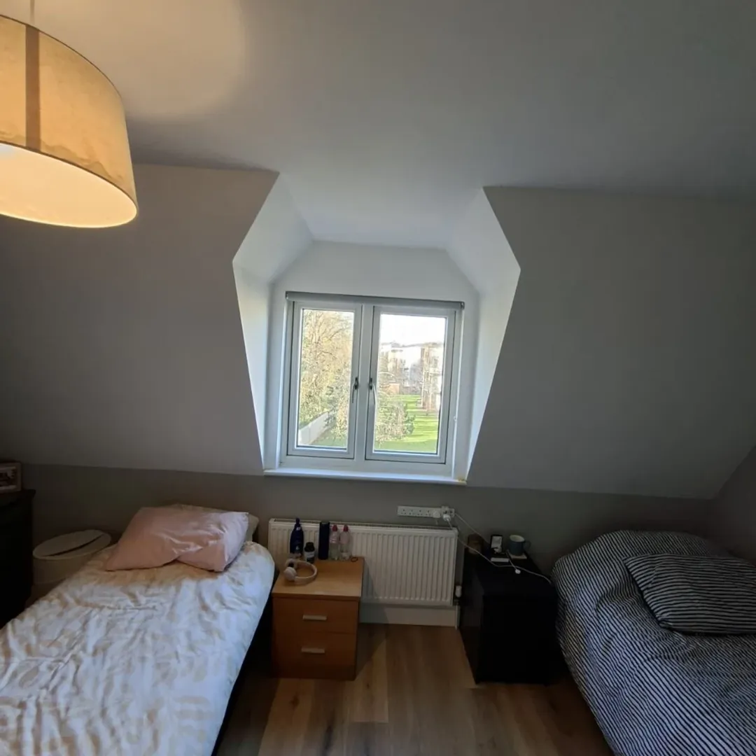 Attic bedroom with twin beds, window, and sloped ceilings.