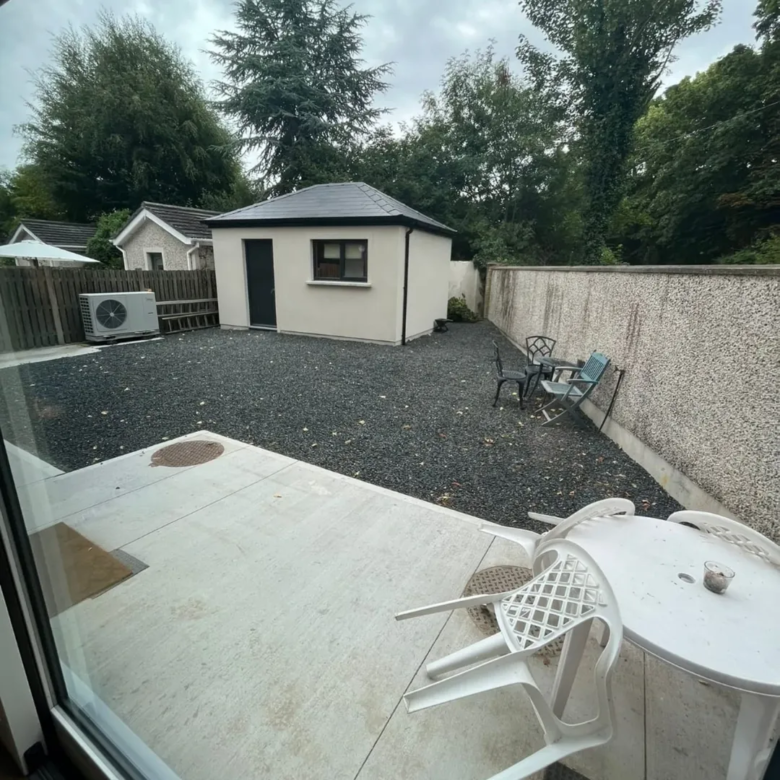 Backyard patio with gravel, outdoor furniture, and modern shed.