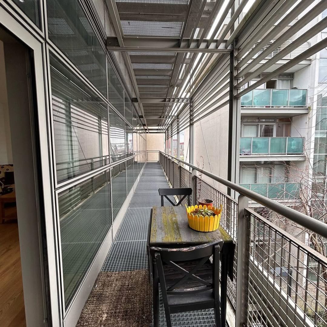 Balcony with table, chairs, and yellow pot with fruit on a sunny day.
