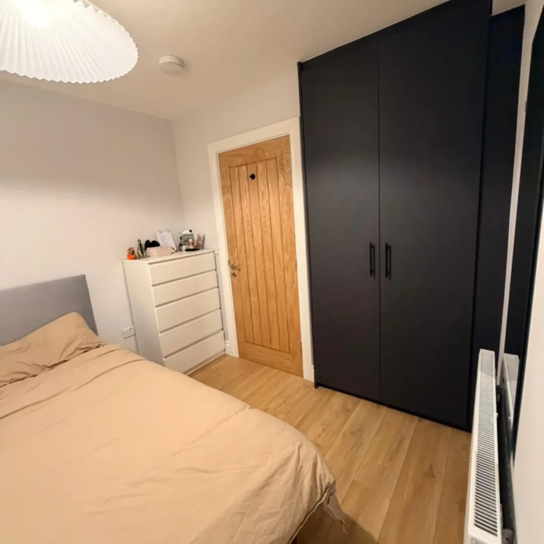 Bedroom with bed, dresser, wardrobe, and wooden door. Minimalist interior design.