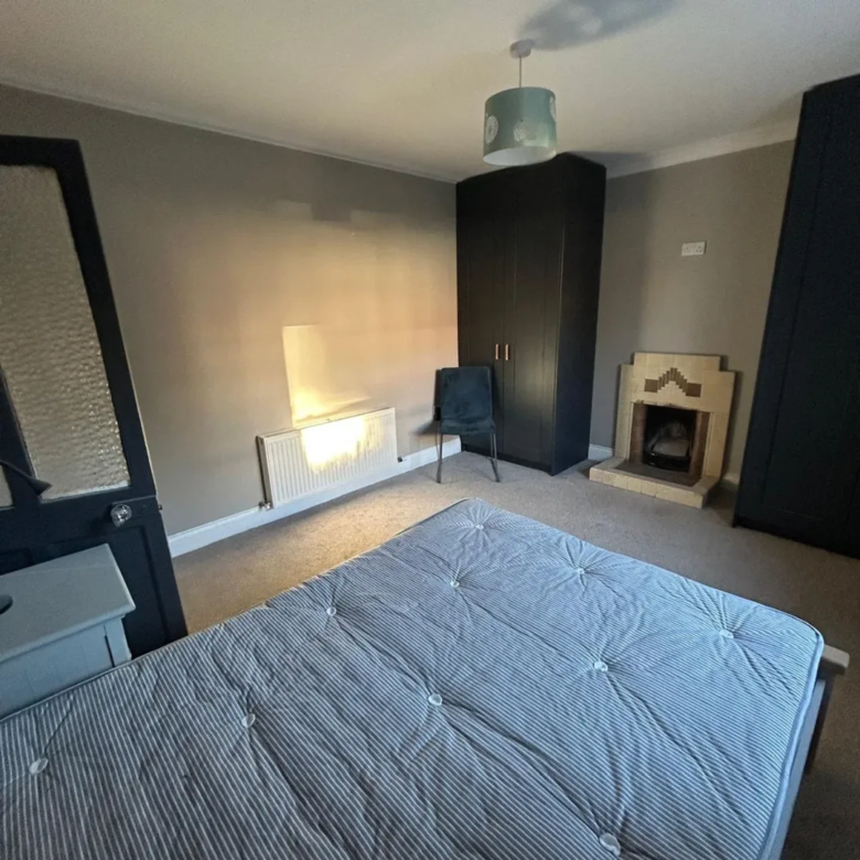 Bedroom with bed, fireplace, and dark wardrobes. Neutral decor.