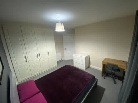 Bedroom featuring a bed, wardrobe, desk, and chair.