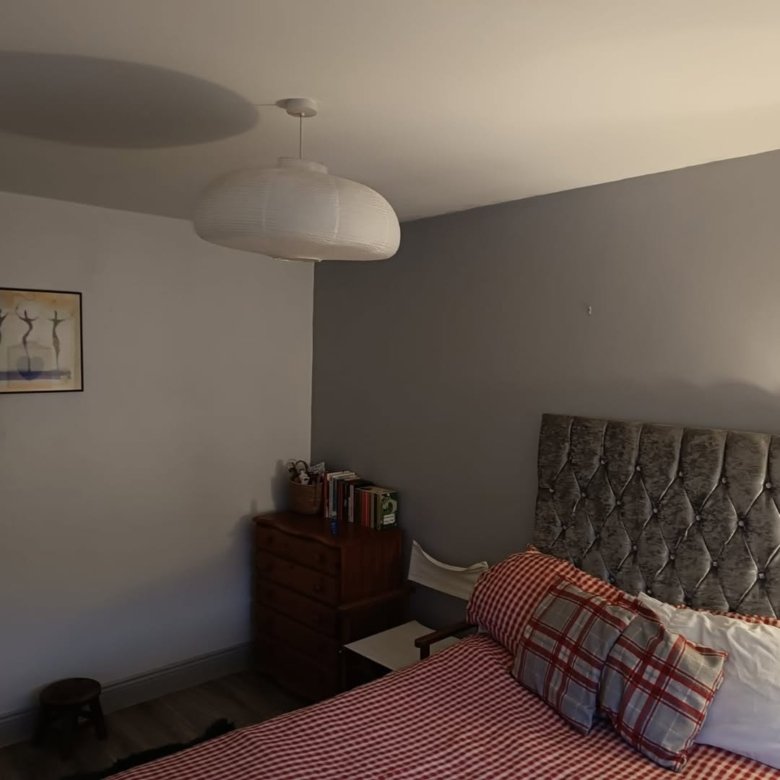 Bedroom interior with gray walls, red and white bedding, and a white pendant light.