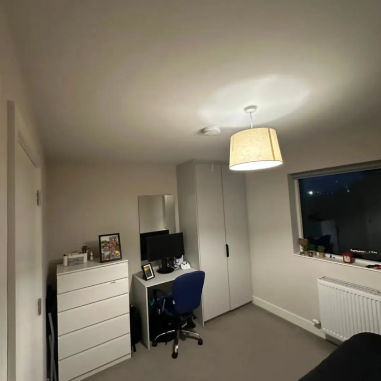 Bedroom interior with desk, chair, wardrobe, and window.