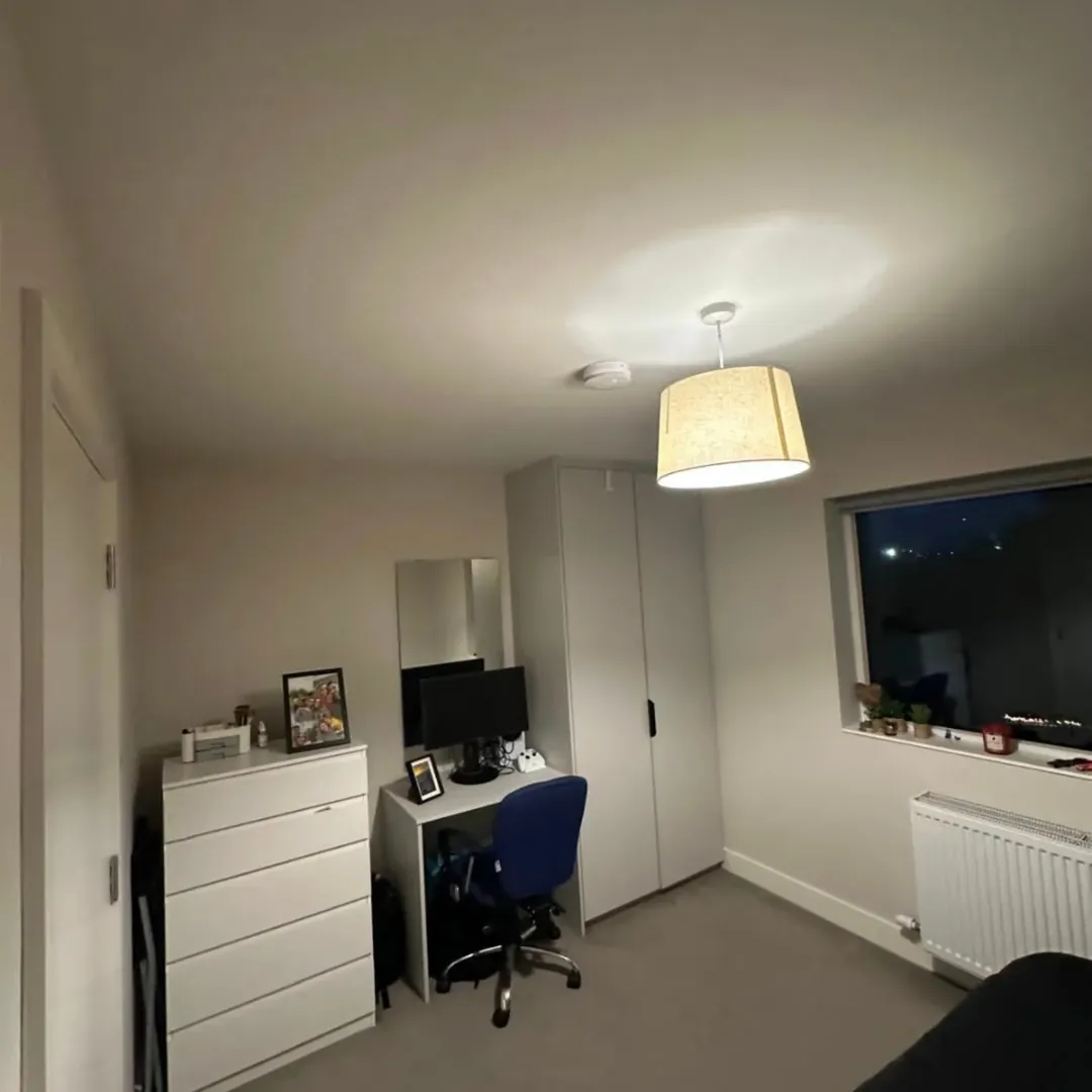 Bedroom interior with desk, chair, wardrobe, and window.
